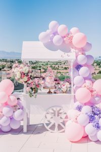 white candy cart with pink and purple balloons